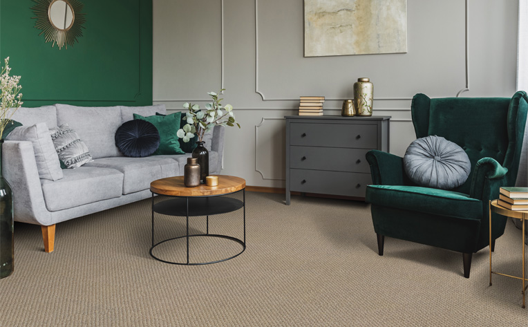 beige carpet in living room with grey couch and green accent chair.